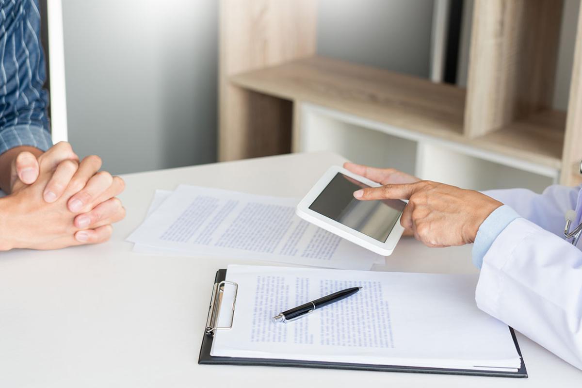 Two people working at a desk, one using a tablet